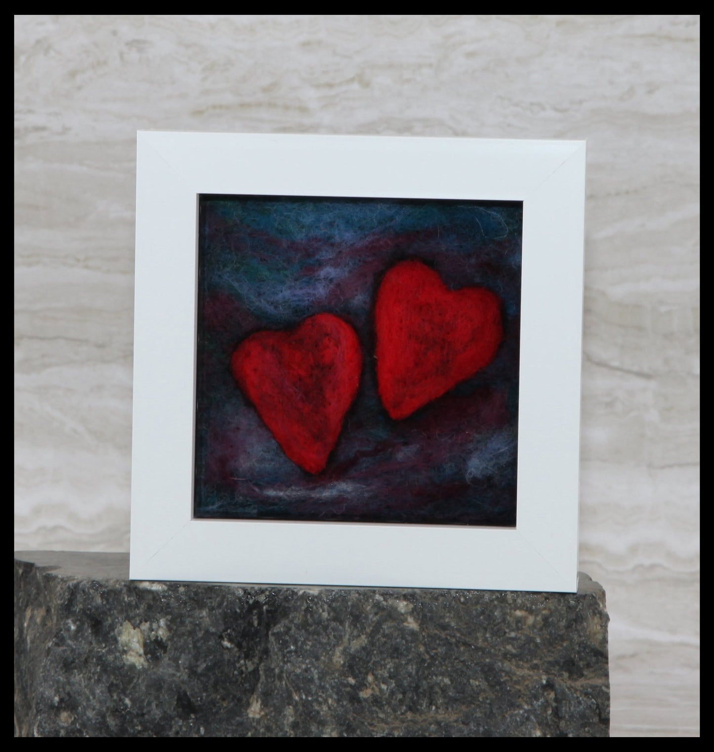 Framed artwork with two red hearts on a dark background