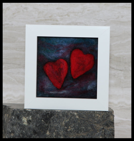 Framed artwork with two red hearts on a dark background