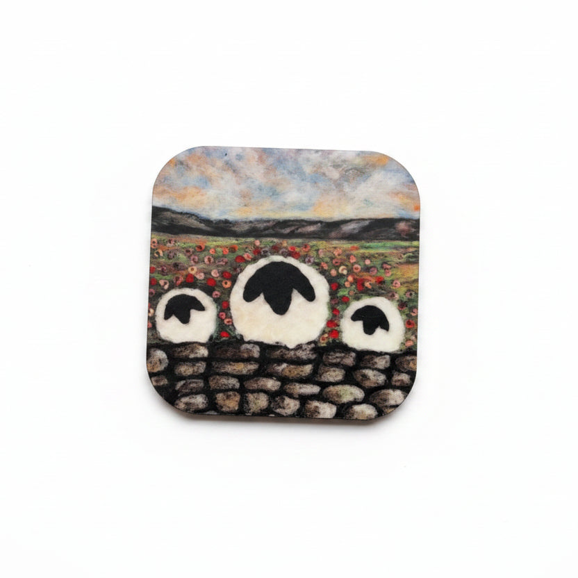 A square ceramic tile coaster featuring a hand-painted design of three sheep in a field, styled on a textured gray concrete surface next to sprigs of lavender.