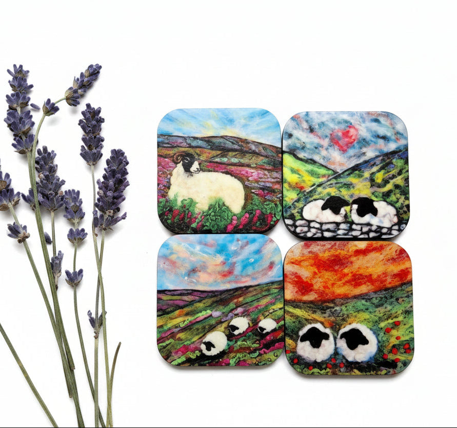 Four square coasters featuring colorful painted scenes of sheep in fields, arranged on a gray textured surface next to a sprig of lavender.