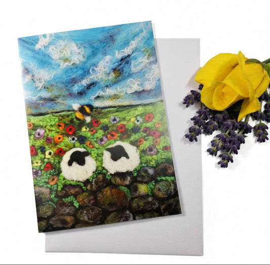 A square art print or card featuring a colorful landscape painting with two white sheep in a flower field under a blue sky, s