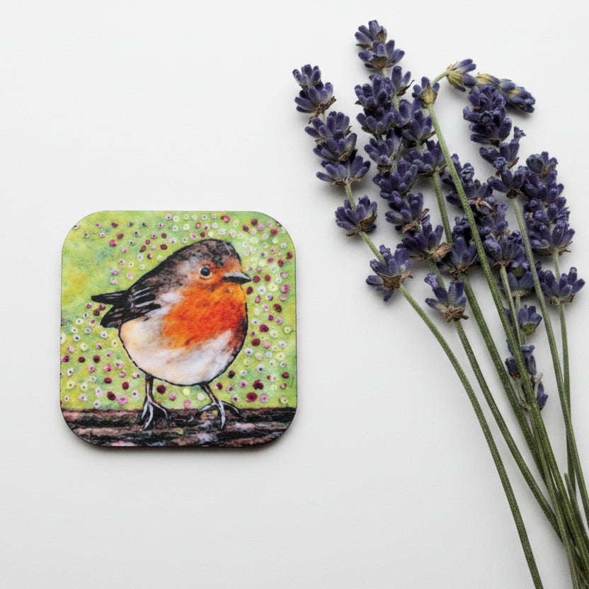 A square coaster featuring a painted robin bird on a textured green and yellow background, styled on a gray concrete surface next to sprigs of lavender.